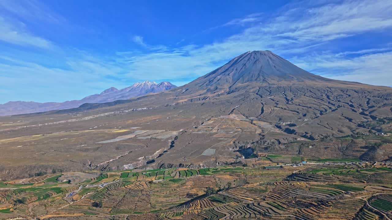 Vista aerea del monte Misti e del Chachani in Perù che mostra colate laviche che scendono lungo i pendii del Misti verso ampi terreni agricoli terrazzati. La diversa prospettiva in altezza enfatizza la scala in una scena drammatica.