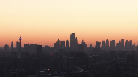 Tight-rising-aerial-shot-of-London-skyline-silhouetted-against-the-dawn-light