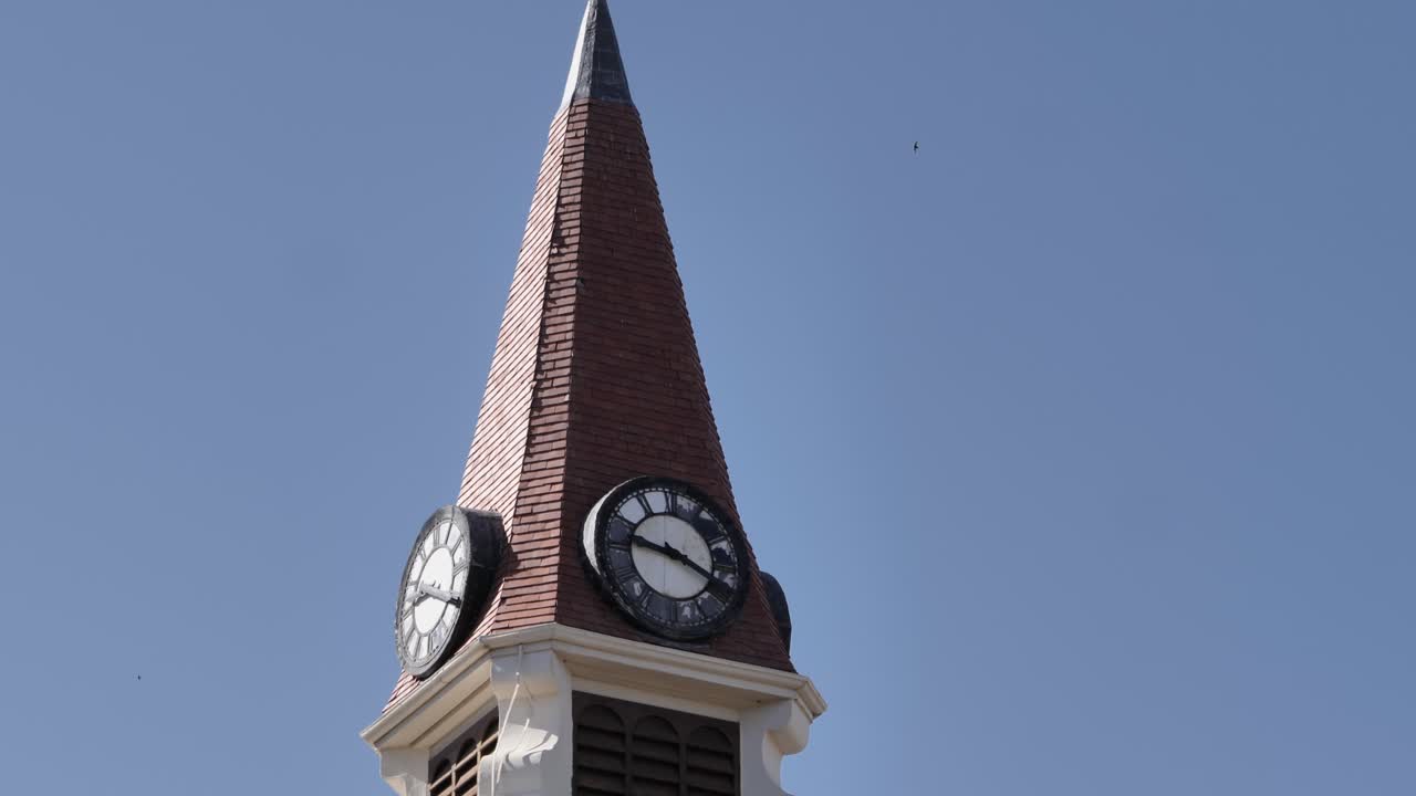 Tilt up stone church clock tower steeple against blue sky, copy space