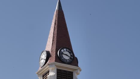 Tilt-up-stone-church-clock-tower-steeple-against-blue-sky,-copy-space