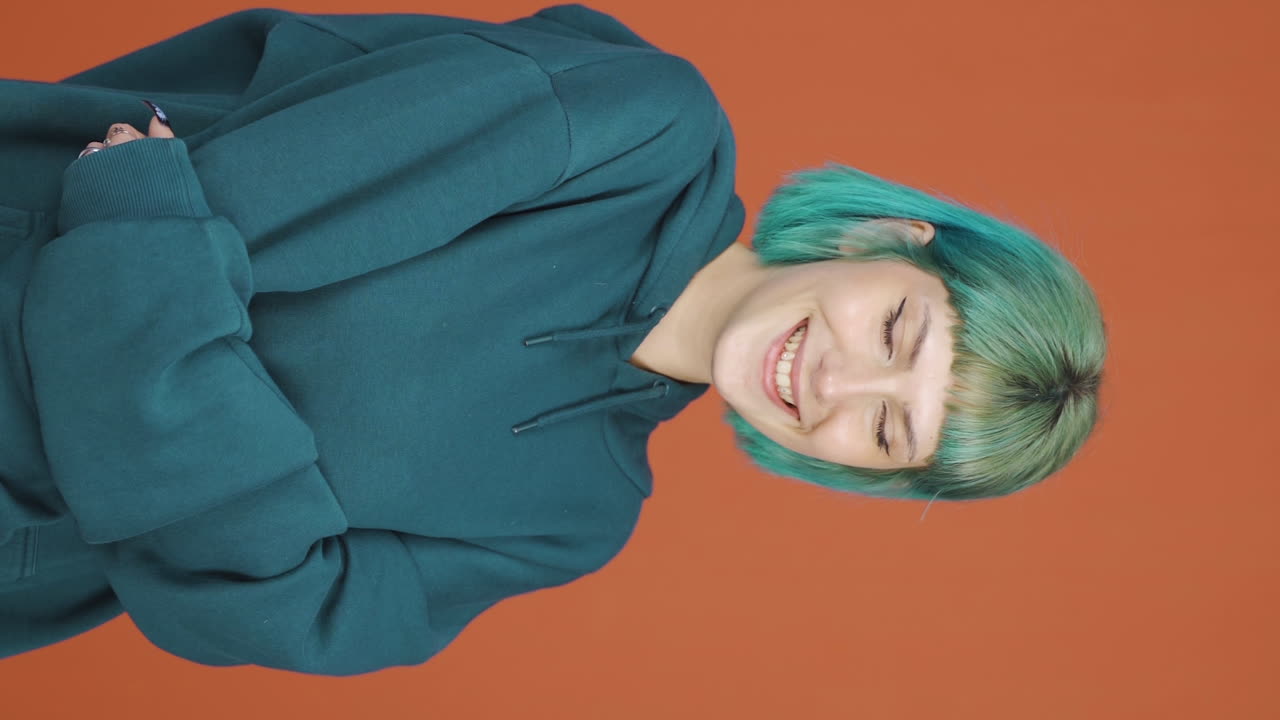 카메라를 위해 귀여운 몸짓을 하는 젊은 여성의 수직 비디오.