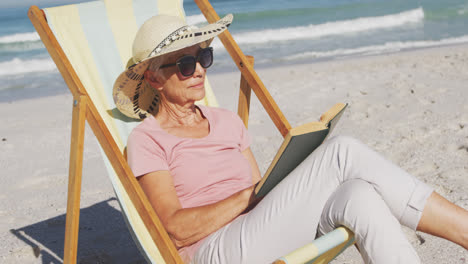 senior caucasian woman sitting on sunbeds at the beach.