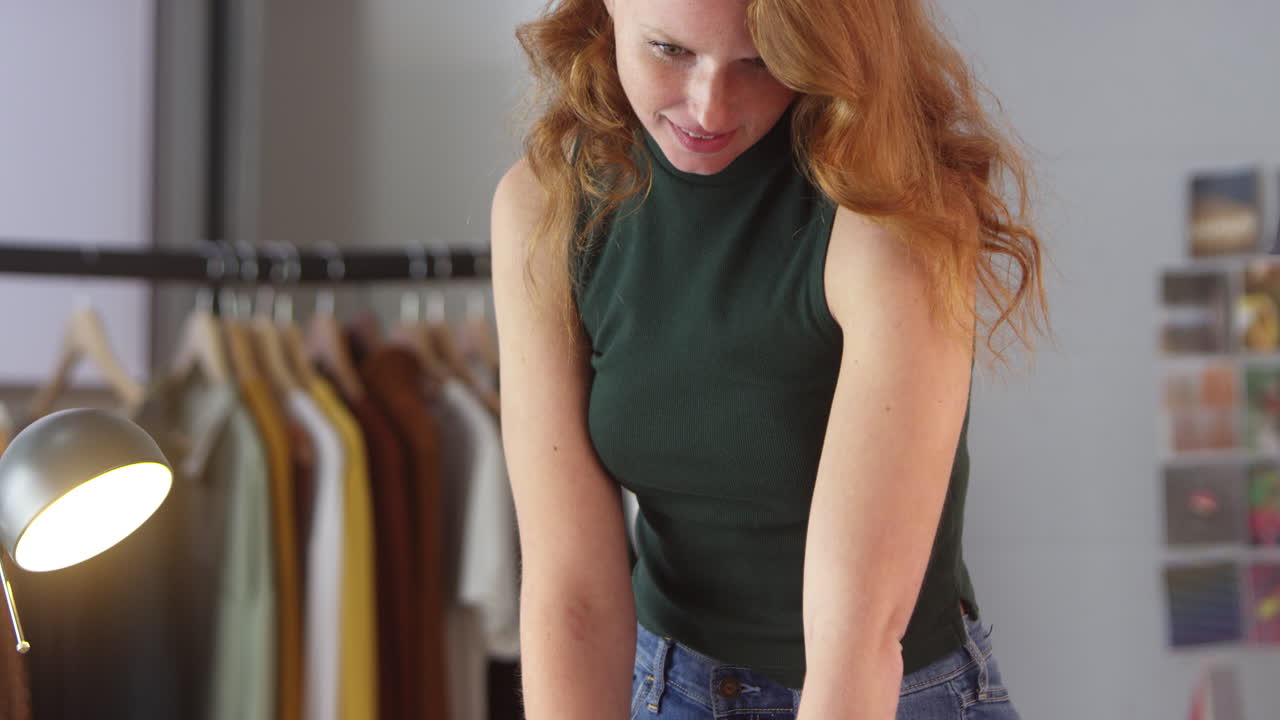 Female Clothes Designer Working In Fashion Studio Drawing Pattern On Fabric In Chalk
