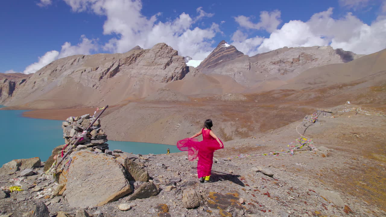 Tilicho Lake Manang Nepal landscape reveals woman enjoying in pink dress, mountain, cold weather, World's Highest Altitude Lake and mountain circuit drone shot 4K