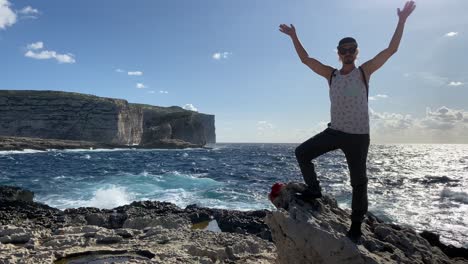 man raises arms and shakes body cheering in front of sea, funny achievement concept