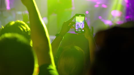 concert audience capturing performance on smartphone with vibrant lights and energetic atmosphere