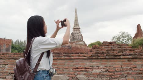 traveler asian woman using smartphone for take a picture while spending holiday trip at ayutthaya, thailand.