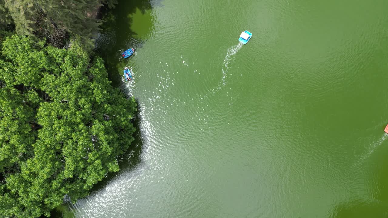 Aerial shot from above showing tourists in small boats on lush forest lake in Santa Lucia, Honduras