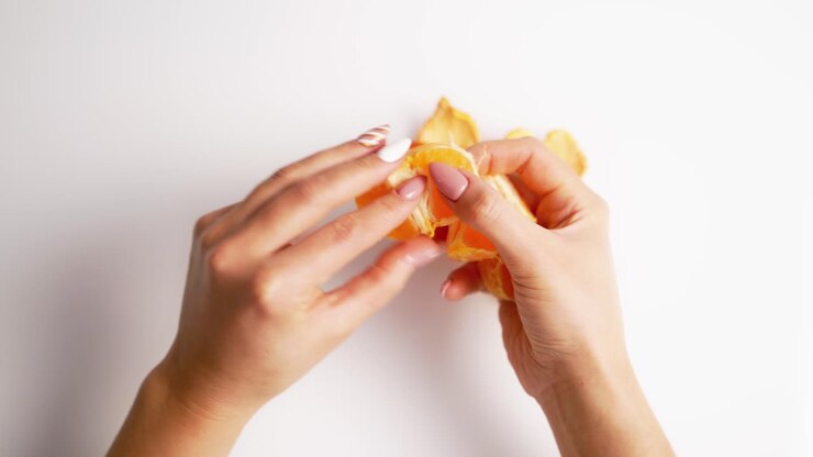 Peeled mandarin in female hands. Close up of mandarin on white background