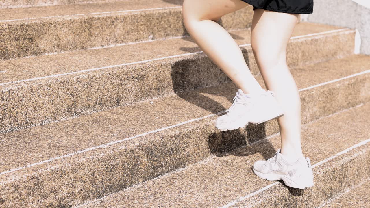 A woman in white sneakers runs up stone steps during a bright outdoor fitness workout