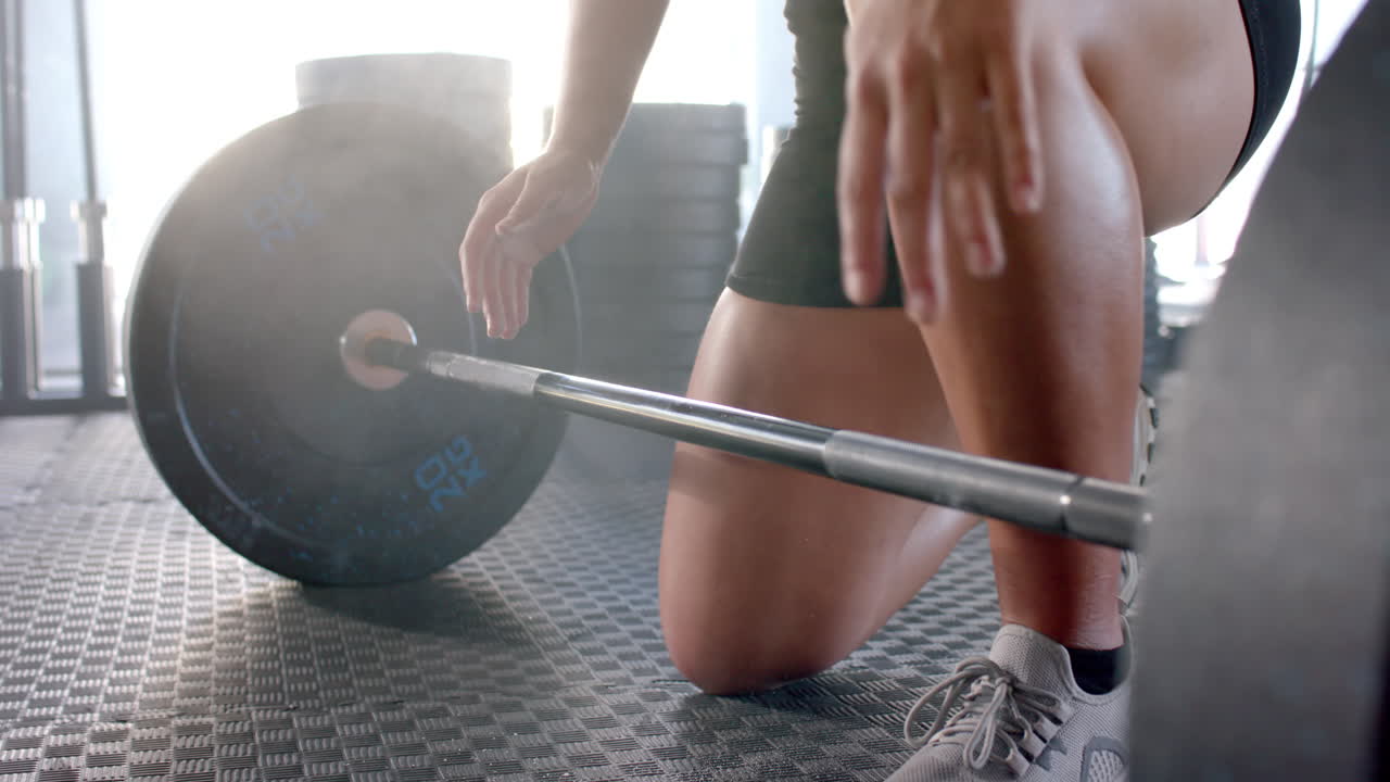 Lifting barbell, woman preparing for weightlifting exercise in gym