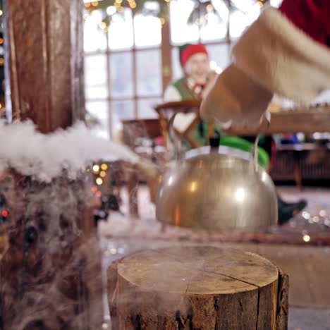 Close up of steaming teapot. Santa Claus's hand is taking the kettle. New Year and Christmas concept. Feast is coming. Specialy decorated room.