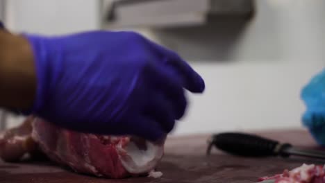 local butcher using sharp knife to clean fresh meat bone, close up