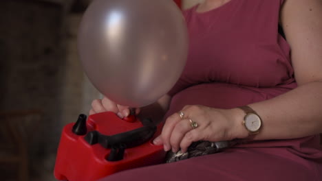 caucasian woman using electronic air balloon pump inflating inside