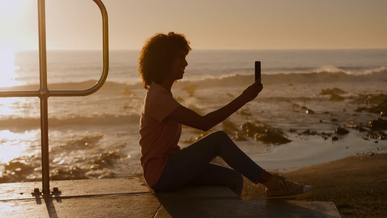 Donna che si scatta un selfie sulla spiaggia al tramonto