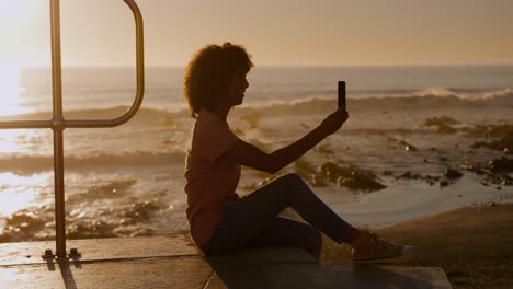 woman taking selfie on beach at sunset