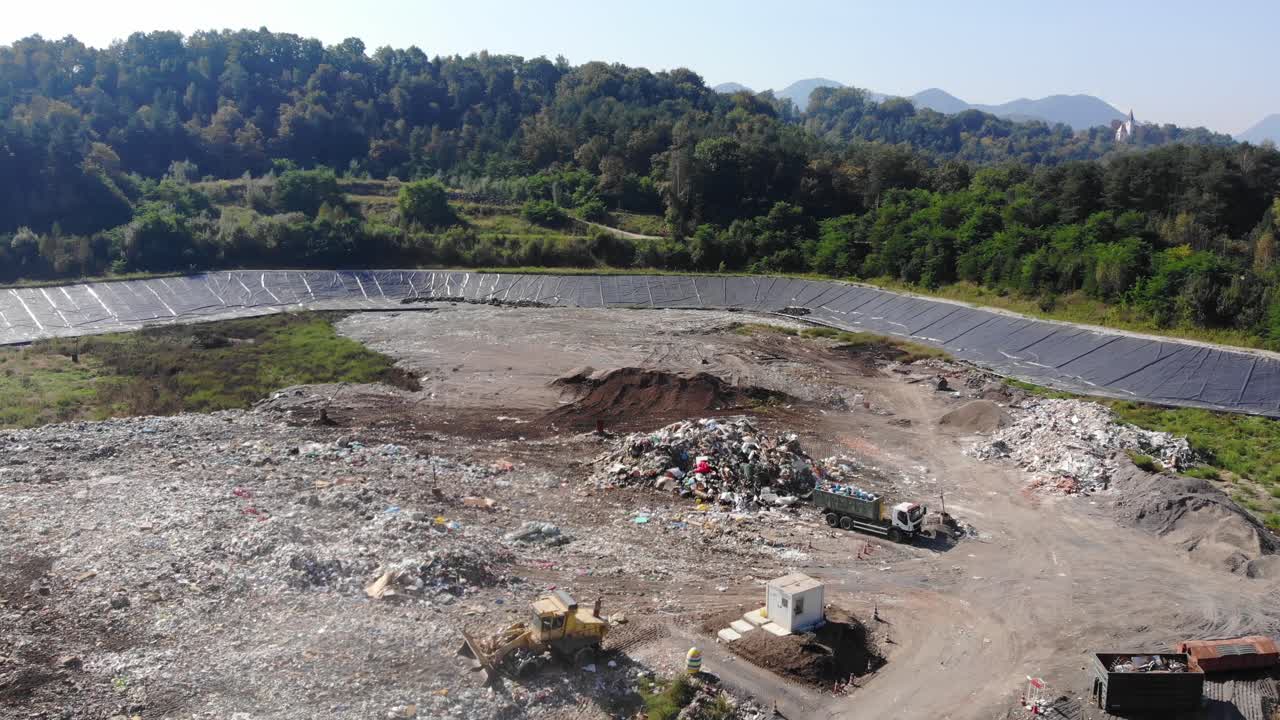 Industrial waste landfill operation with loader and dump truck working below, Aerial dolly in shot