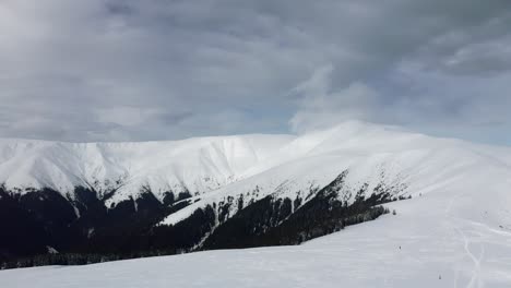 Expansive-snowy-landscape-of-Papusa-Peak-with-clouds-above,-in-Iezer-Papusa,-Romania