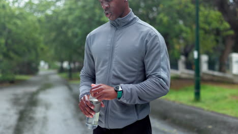 man drinking water during a rainy workout