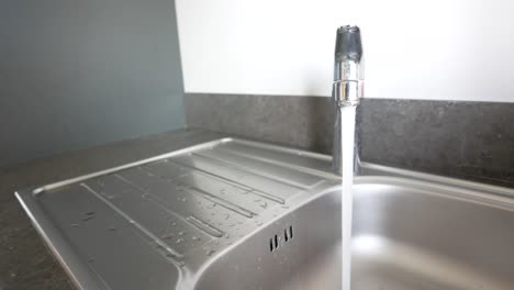 close-up of a kitchen sink with water running from the faucet.