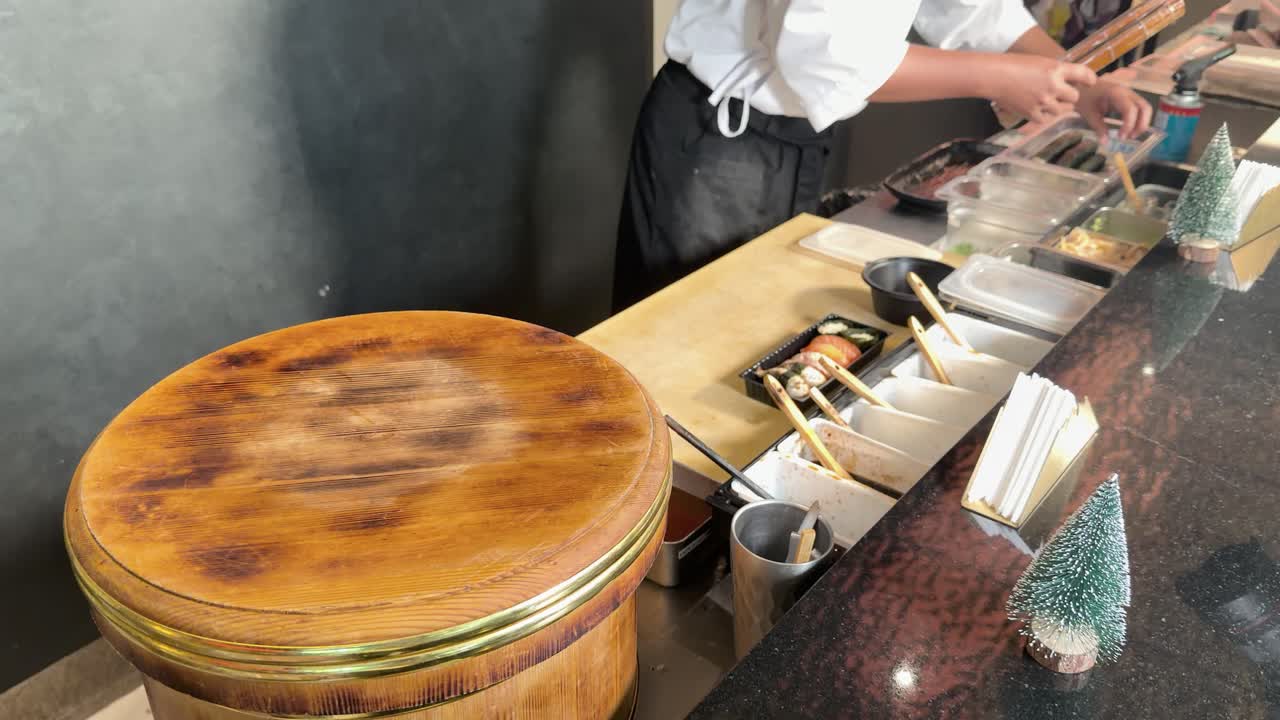 Professionel sushikok tilbereder laks nigiri ved træbord med et stabilt sidekameravinkel