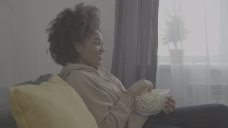 young african american woman enjoying a movie and eating popcorn