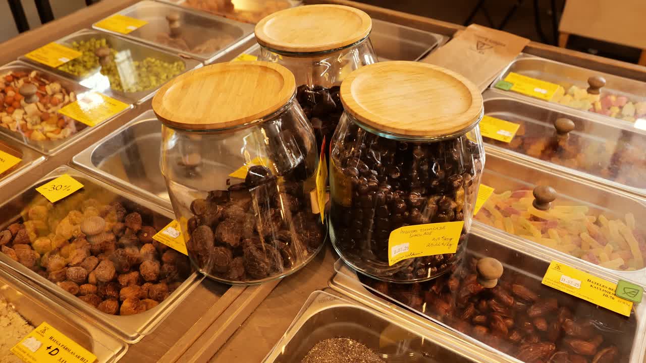 Colorful dried fruits, nuts displayed in bulk shop jars for eco conscious living