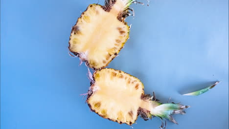 Stoppen-Sie-Die-Bewegung-Der-Halbierten-Ananas-Auf-Isoliertem-Blauem-Hintergrund