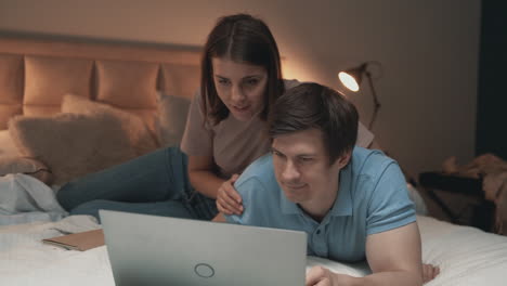 Pareja-Joven-Usando-Laptop-En-La-Cama,-Mujer-Y-Hombre,-Compartiendo-Momentos