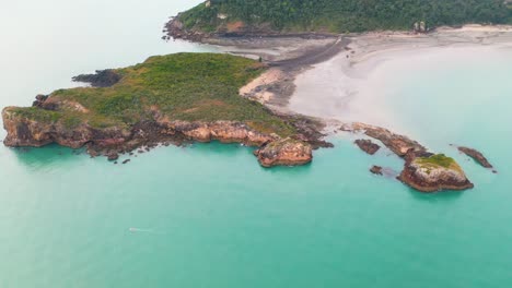 aerial: tropical australia coastline, with small boat sailing in turquoise sea