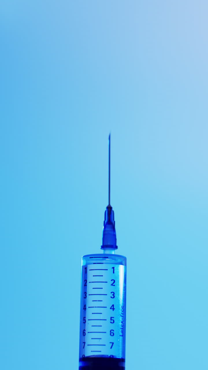 Vertical video of laboratory syringe with copy space on blue background