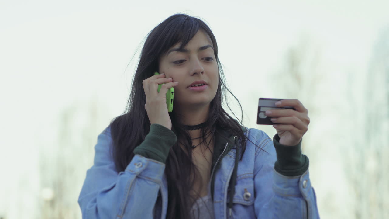 una adolescente seria dictando el número de la tarjeta por teléfono.
