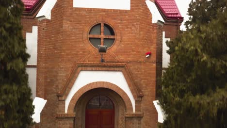 un dron aéreo se acerca y sobrevuela la iglesia de techo rojo en un pequeño pueblo comunitario en la provincia de rumania