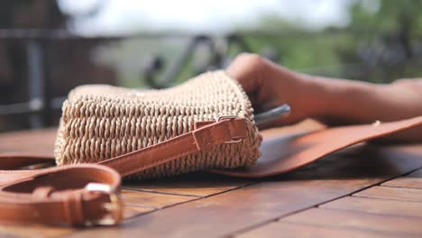 close up of a brown woven handbag with leather strap on a wooden table