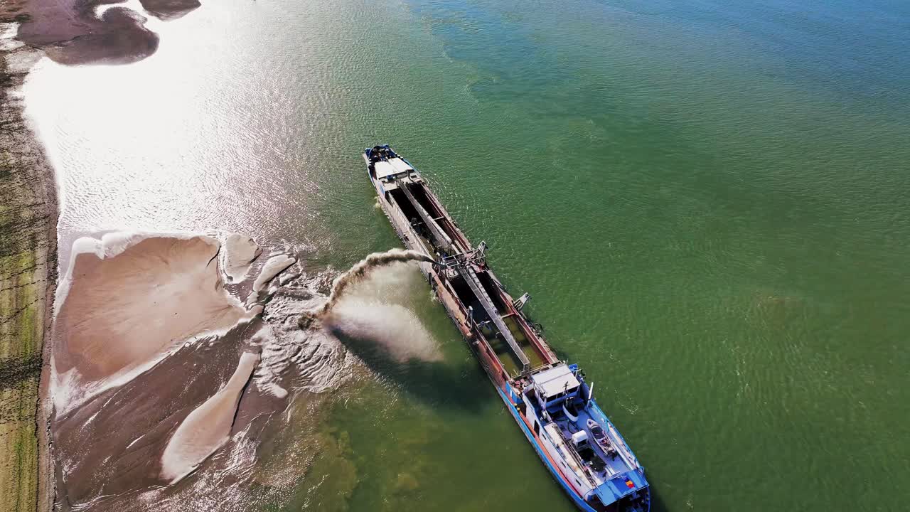 Aerial top shot of a dredger unloading dredged sand on a big river, sunny day