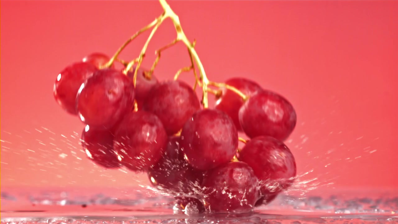 Uva rossa fresca che schizza nell'acqua al rallentatore