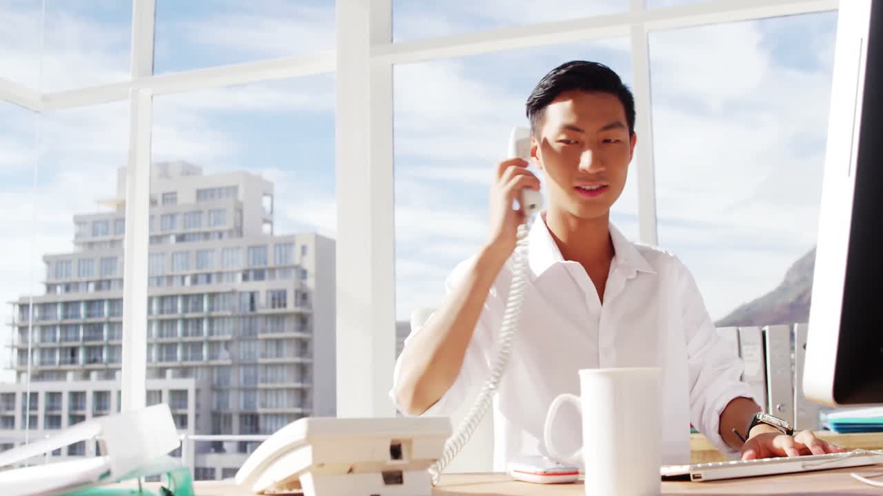 パソコンで電話しながらタイピングする男性