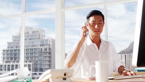 a man calling and typing on computer