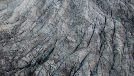 flyover above iceland glacier, with cracks and crevasses visible in ice