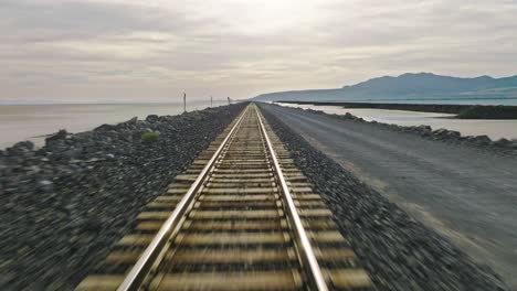 AERIAL---Speeding-along-railroad-tracks,-Great-Salt-Lake,-Utah,-forward-POV-shot