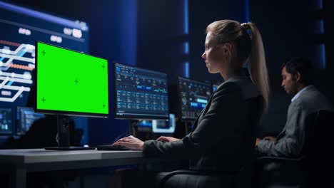 científica de datos femenina confiada trabaja en una pantalla clave de croma verde en una gran sala de control de infraestructura. los especialistas usan computadoras que muestran gráficos, información. equipo profesional de la sala de control