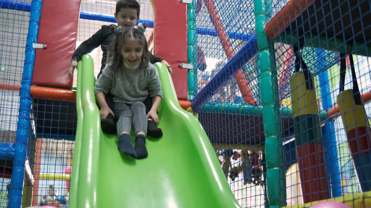 Adorable happy little kids sliding in pool with colorful balls. 5 year old. Slow motion