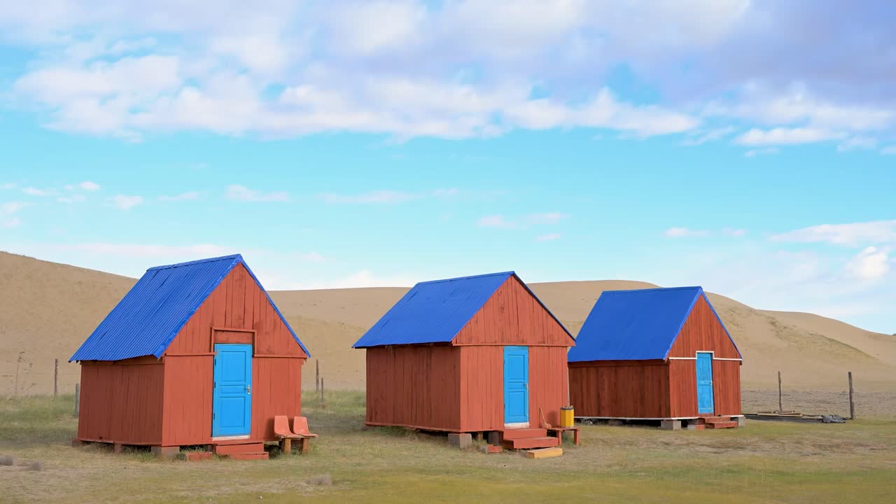 Vibrant wooden cabins with blue roofs provide tourist accommodation in rural Mongolia, near Durgun Nuur lake. A remote hostel complex set against the region's arid terrain