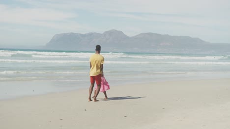 Afroamerikanischer-Vater-Und-Tochter-Halten-Sich-An-Den-Händen-Und-Springen-Am-Strand