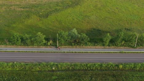 Aerial-shot-of-people-riding-bicycles-along-the-lane-through-countryside-landscape