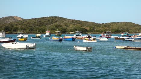 El-Hombre-Rema-En-Una-Balsa-Entre-Botes-De-Madera-En-Una-Tranquila-Bahía-Tropical