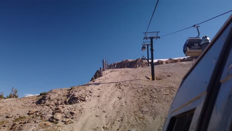 Gimbal-static-shot-from-gondola-looking-backward-up-the-mountain-as-other-gondolas-go-by-during-the-descent-in-Mammoth,-California