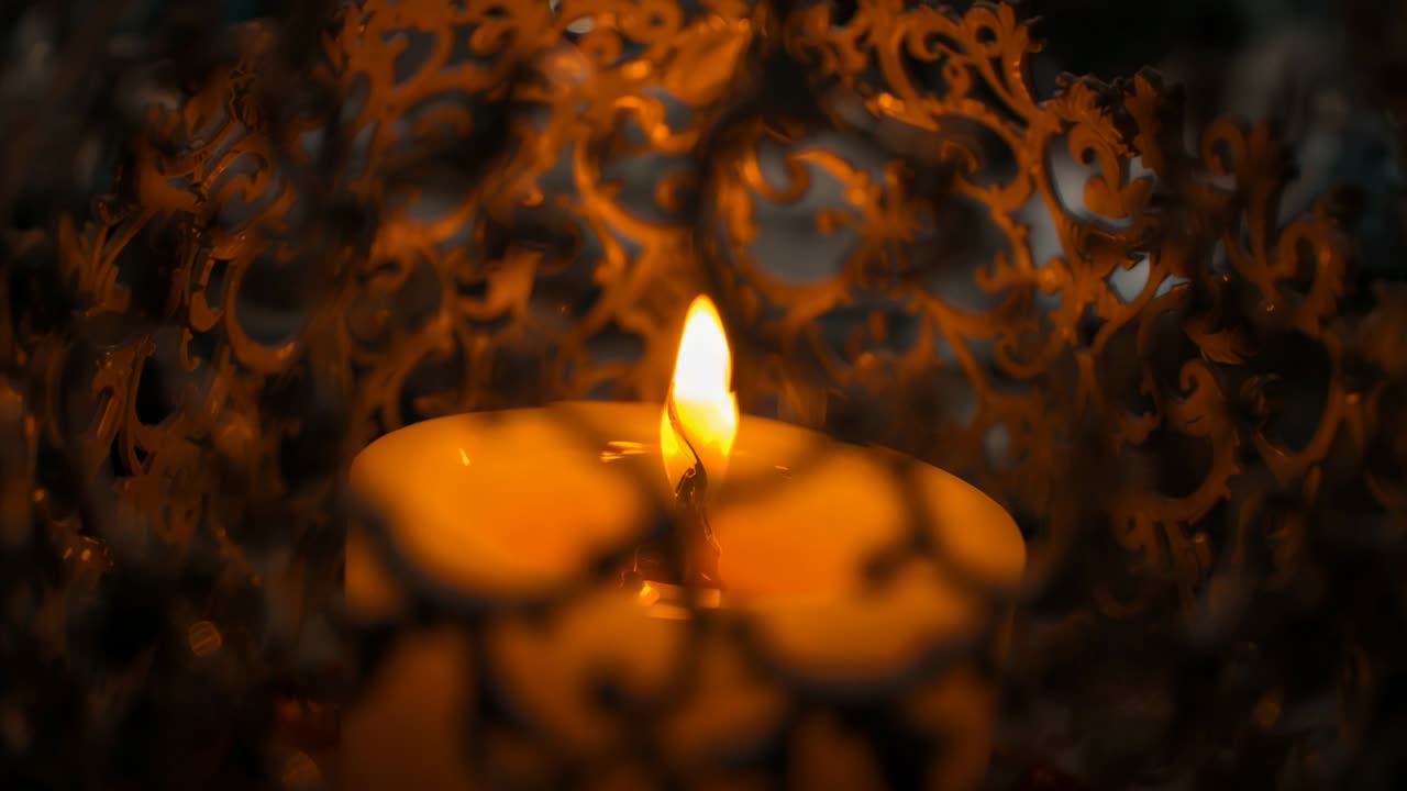 Draft entering filigree cage causing white candle flame quivering, forming wax pool in dim interior