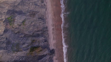 Drohnenaufnahme-Von-Oben-Nach-Unten,-Die-Sich-Von-Den-Wellen-Und-Klippen-Des-Grünen-Meeres-An-Der-Jurassic-Coast,-Dorset,-Großbritannien,-Nach-Oben-Bewegt