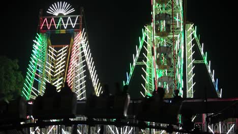 carnival with ferris wheel, bright colourful lights, car carousel at night closeup